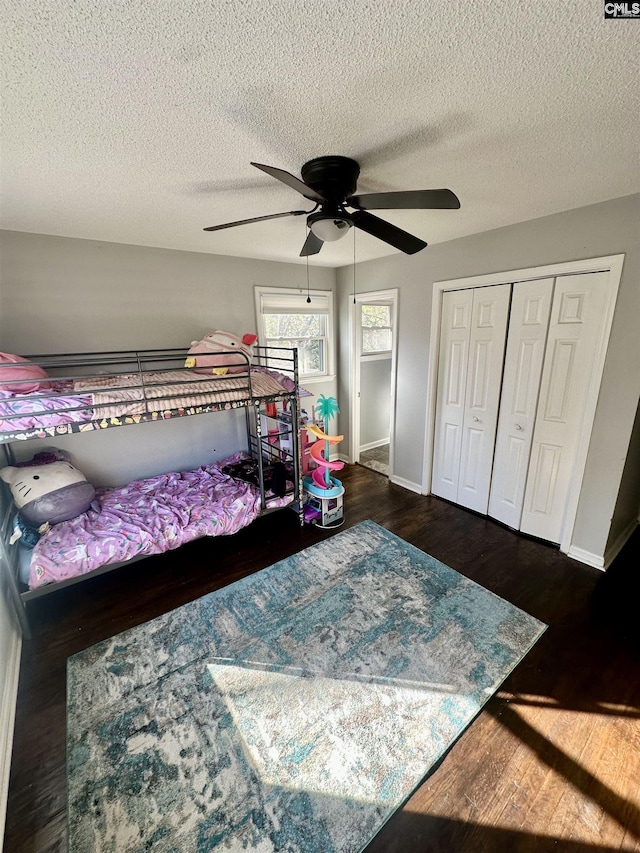 bedroom featuring a closet, a textured ceiling, dark hardwood / wood-style floors, and ceiling fan