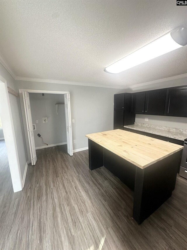 interior space with dark hardwood / wood-style flooring, ornamental molding, a textured ceiling, and a kitchen island