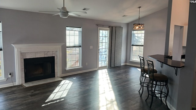 living room featuring ceiling fan, dark hardwood / wood-style flooring, a fireplace, and vaulted ceiling