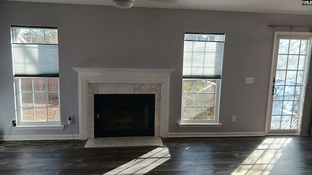 unfurnished living room with a tile fireplace and dark wood-type flooring