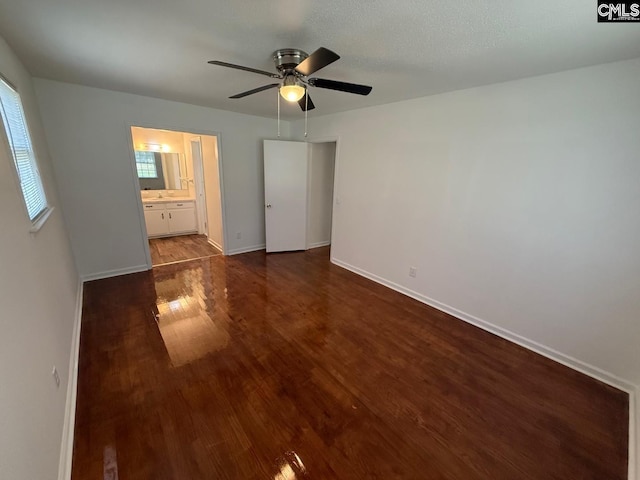 unfurnished bedroom with baseboards, ceiling fan, wood finished floors, and connected bathroom