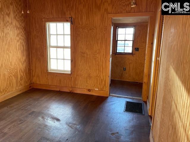 empty room featuring wood walls and dark wood-type flooring