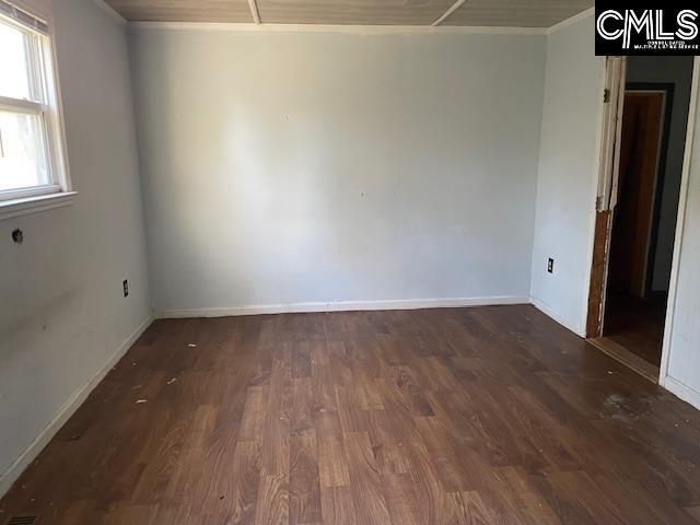 unfurnished room with ornamental molding and dark wood-type flooring