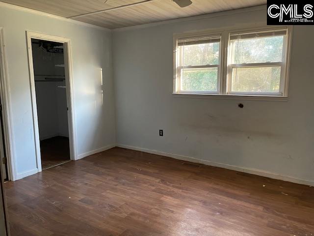 unfurnished bedroom with a walk in closet, dark wood-type flooring, wood ceiling, and a closet