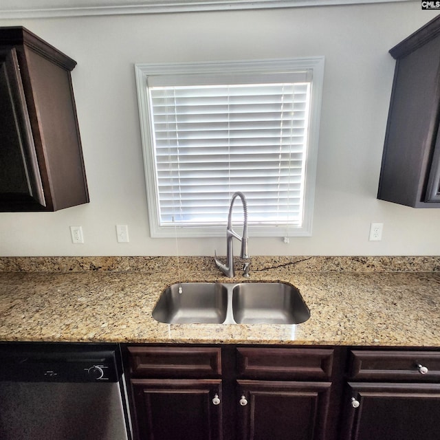 kitchen with stainless steel dishwasher, light stone counters, dark brown cabinetry, and sink