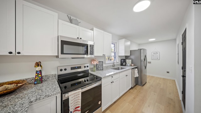 kitchen featuring light stone counters, stainless steel appliances, white cabinetry, and sink