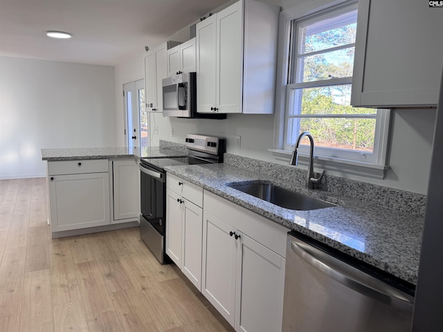 kitchen with white cabinets, light wood-type flooring, stainless steel appliances, and sink