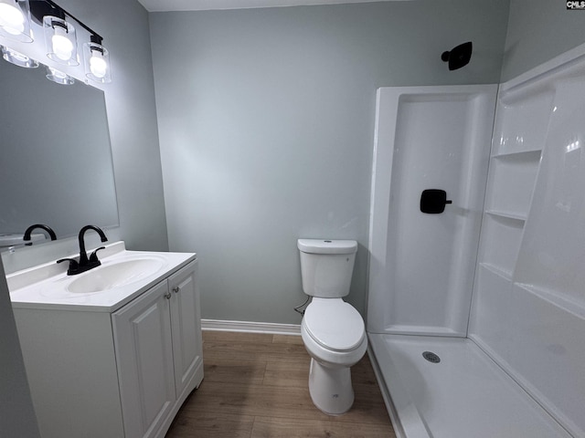 bathroom featuring walk in shower, hardwood / wood-style floors, vanity, and toilet