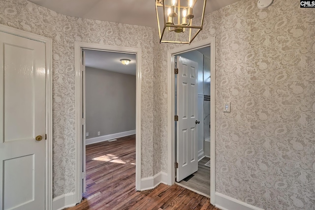 hall with dark hardwood / wood-style flooring and an inviting chandelier