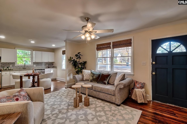 living room with a healthy amount of sunlight, crown molding, ceiling fan, and dark wood-type flooring