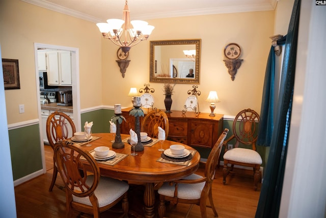 dining space with hardwood / wood-style floors, a notable chandelier, and ornamental molding