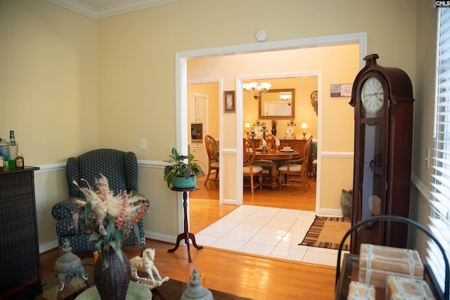 sitting room with crown molding, light tile patterned flooring, and an inviting chandelier