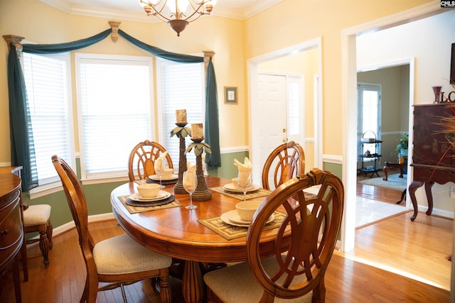 dining area with crown molding, an inviting chandelier, and hardwood / wood-style flooring