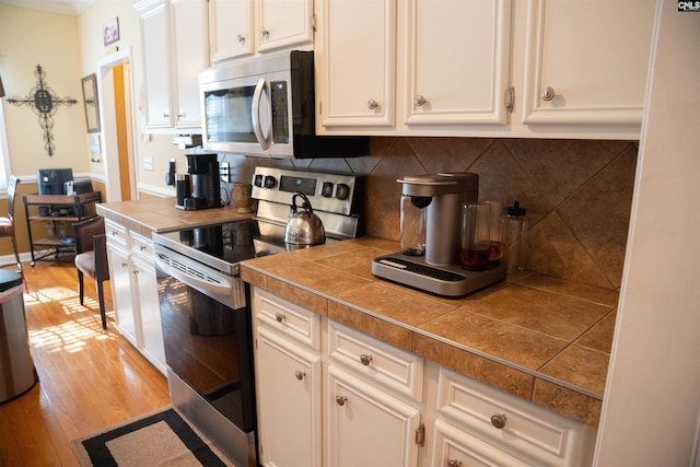 kitchen featuring decorative backsplash, stainless steel appliances, light hardwood / wood-style flooring, and tile counters