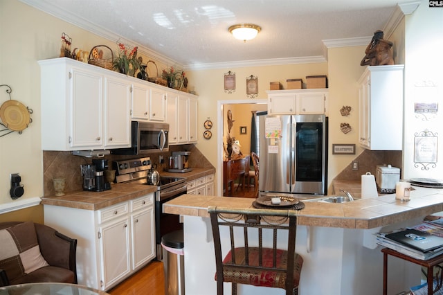 kitchen featuring tile countertops, a kitchen breakfast bar, and appliances with stainless steel finishes