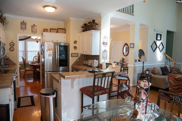 kitchen with tile counters, white cabinetry, kitchen peninsula, and appliances with stainless steel finishes