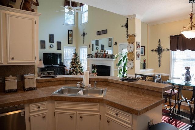 kitchen with kitchen peninsula, backsplash, sink, pendant lighting, and dishwasher