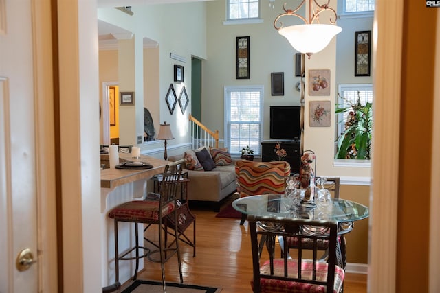 living room with a towering ceiling, crown molding, and light hardwood / wood-style flooring