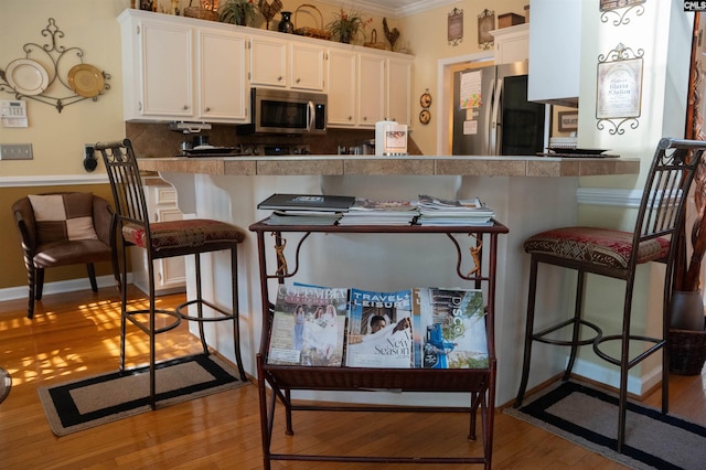 kitchen with a kitchen breakfast bar, kitchen peninsula, white cabinets, and stainless steel appliances