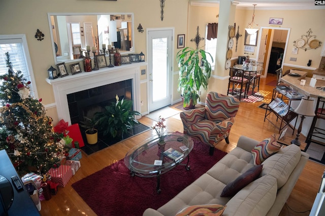 living room with hardwood / wood-style floors, crown molding, and a tiled fireplace