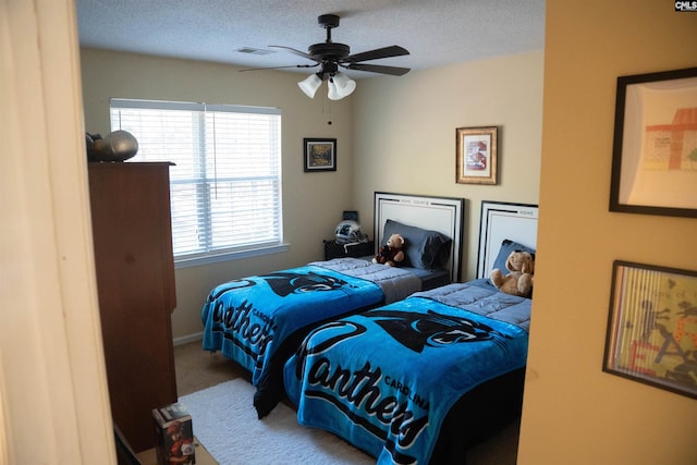 carpeted bedroom featuring ceiling fan and a textured ceiling