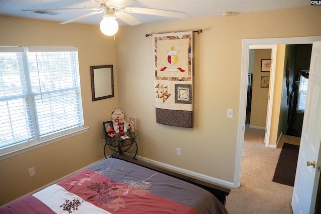 bedroom featuring ceiling fan, light carpet, and multiple windows