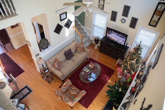 living room featuring wood-type flooring, a towering ceiling, ceiling fan, and a healthy amount of sunlight