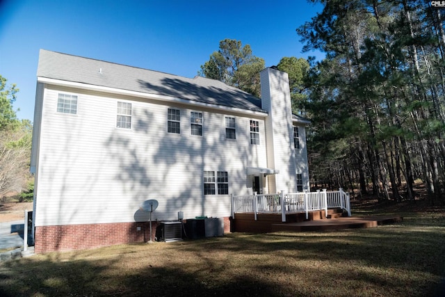 rear view of property with a lawn, a deck, and central AC