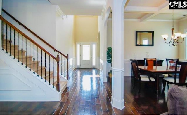 entryway with ornamental molding, coffered ceiling, dark wood-type flooring, beam ceiling, and an inviting chandelier