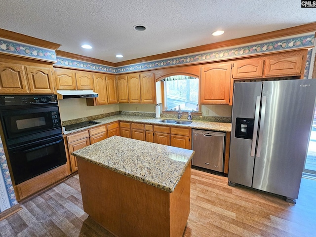 kitchen with sink, stainless steel appliances, light hardwood / wood-style flooring, a textured ceiling, and a kitchen island