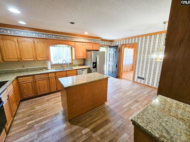 kitchen featuring a center island, sink, light wood-type flooring, ornamental molding, and appliances with stainless steel finishes