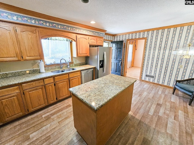 kitchen featuring sink, stainless steel appliances, light hardwood / wood-style floors, a textured ceiling, and a kitchen island