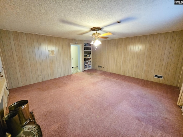 spare room featuring carpet, a textured ceiling, and wooden walls