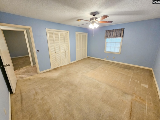 unfurnished bedroom with multiple closets, ceiling fan, carpet, and a textured ceiling