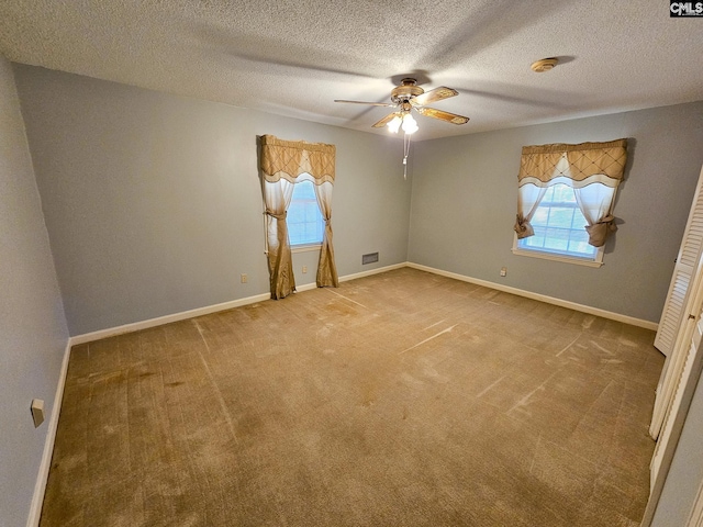 empty room featuring ceiling fan, carpet floors, and a textured ceiling