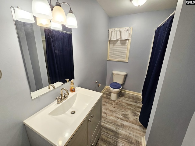 bathroom with hardwood / wood-style floors, vanity, toilet, and a notable chandelier