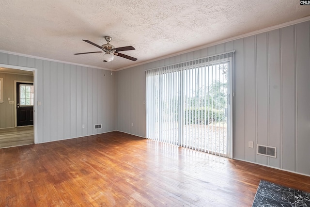 spare room featuring wood-type flooring, a textured ceiling, ceiling fan, and a healthy amount of sunlight