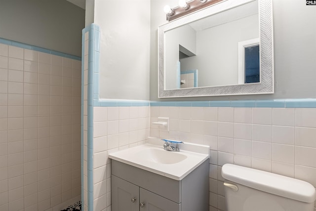 bathroom featuring vanity, toilet, and tile walls