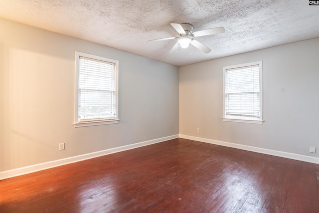 empty room featuring a textured ceiling, dark hardwood / wood-style flooring, and a wealth of natural light