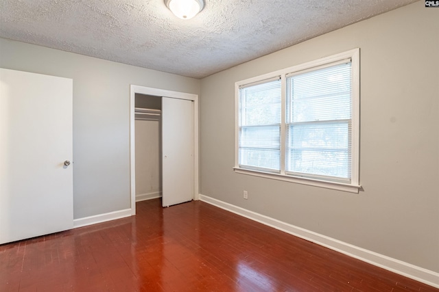 unfurnished bedroom with a closet, dark wood-type flooring, and a textured ceiling