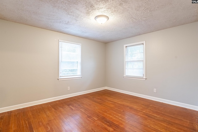 unfurnished room with wood-type flooring, a textured ceiling, and a wealth of natural light