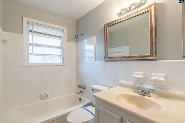 full bathroom with vanity, toilet, tiled shower / bath, and tile walls