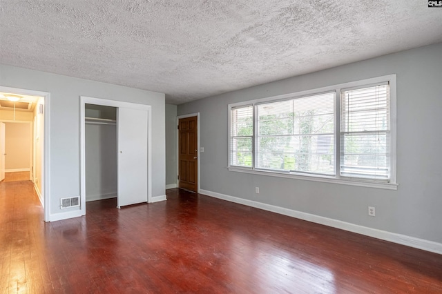 unfurnished bedroom with dark wood-type flooring, a textured ceiling, and a closet