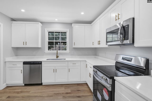 kitchen with white cabinets, light wood-type flooring, sink, and appliances with stainless steel finishes