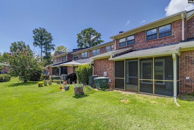 rear view of house with a lawn and a sunroom