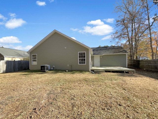 rear view of property with a lawn, a wooden deck, and central AC