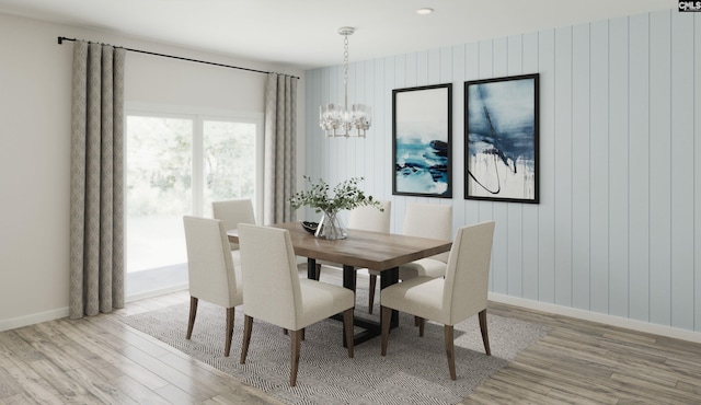 dining area featuring wood walls, an inviting chandelier, and light wood-type flooring