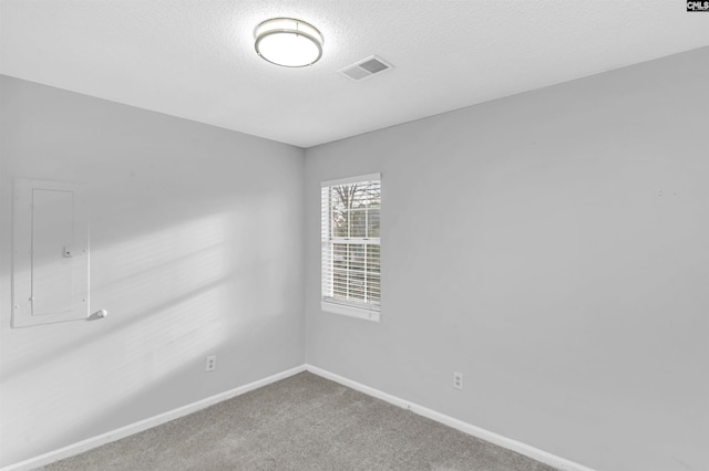 carpeted empty room featuring electric panel and a textured ceiling