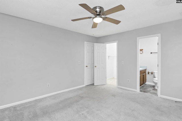 unfurnished bedroom with ensuite bathroom, a closet, ceiling fan, and light carpet