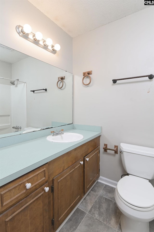 bathroom featuring a textured ceiling, vanity, toilet, and walk in shower